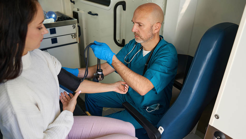 Mutélios médecine itinérante, femme se faisant prendre la tension par un médecin dans un camion de médecine itinérante
