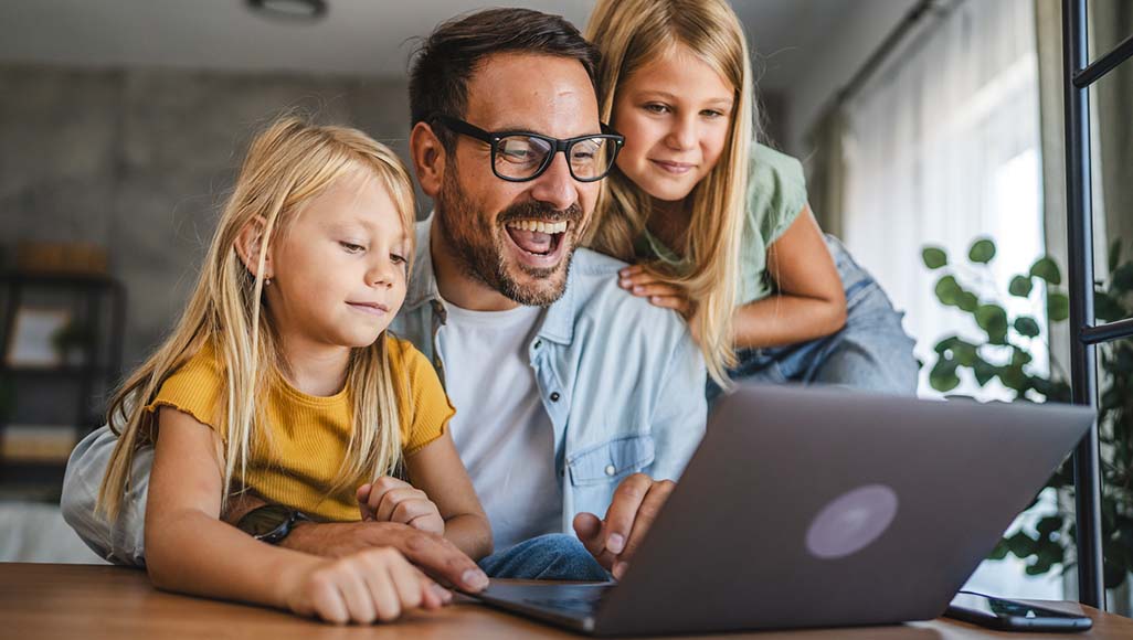 Mutélios Le Mag Online N°4 - Le + Mutélios Parentech, père et ses deux filles penchés au dessus d'un ordinateur