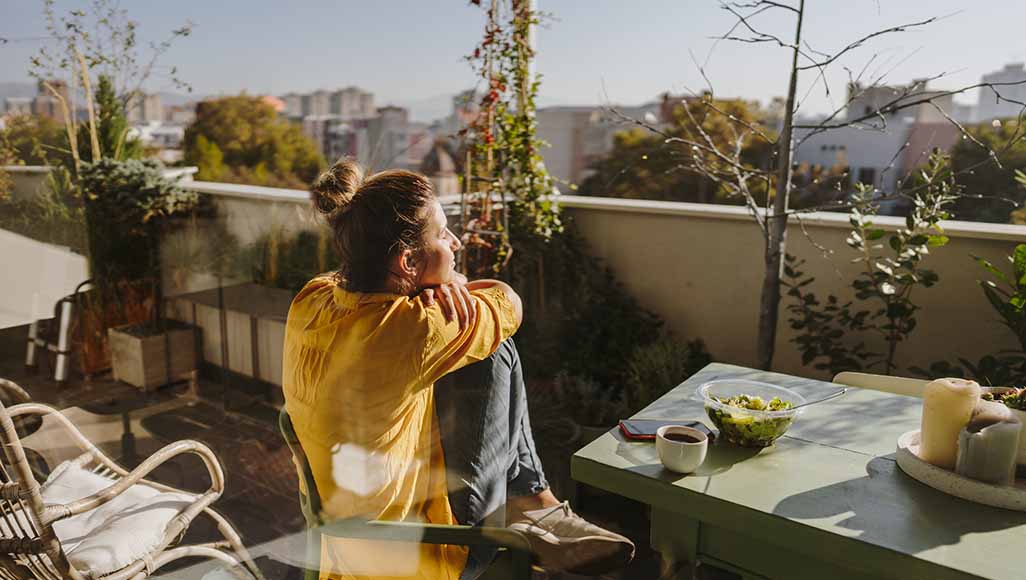 Mutélios Bienfaits Printemps Femme heureuse assise sur une chaise sur son balcon