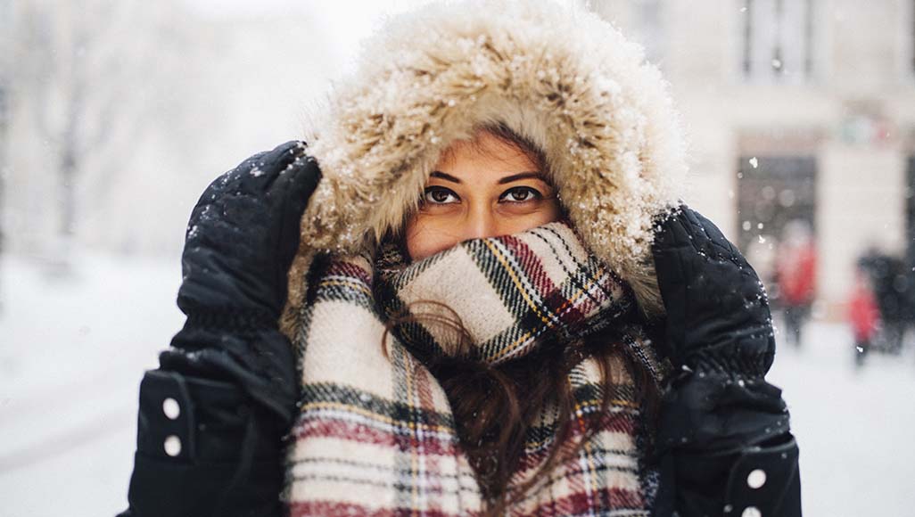 Mutélios craindre le froid, femme emmitouflée dans un gros manteau et écharpe avec de la neige