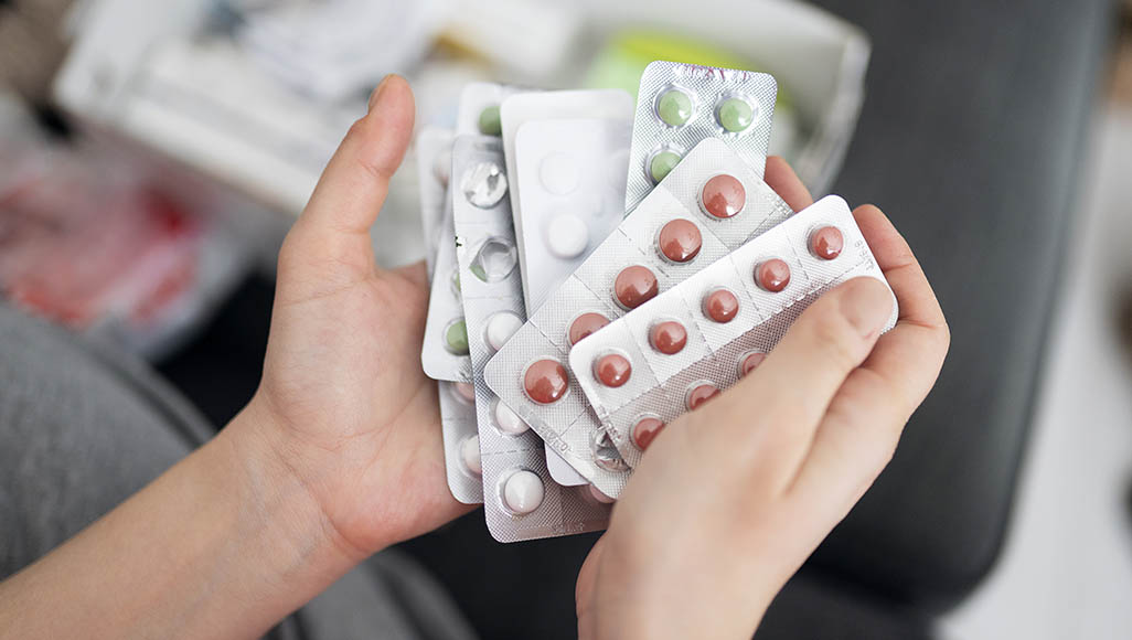 Mutélios ranger son armoire à pharmacie, personne tenant des plaquettes de médicaments dans sa main