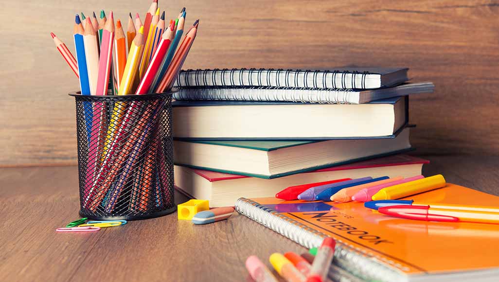 Mutélios budget fournitures scolaires, cahiers et crayons sur un bureau